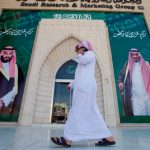 A man speaks on the phone as he walks past posters depicting Saudi Arabia's King Salman