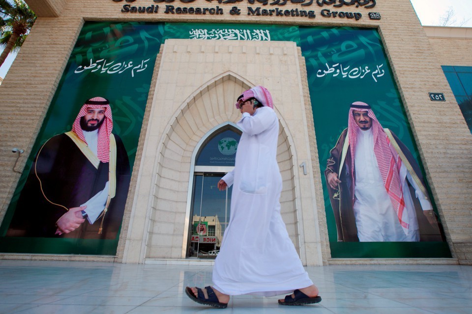 A man speaks on the phone as he walks past posters depicting Saudi Arabia's King Salman