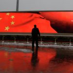 Человек на фоне экрана с китайским флагом, исключили из Компартии за коррупцию