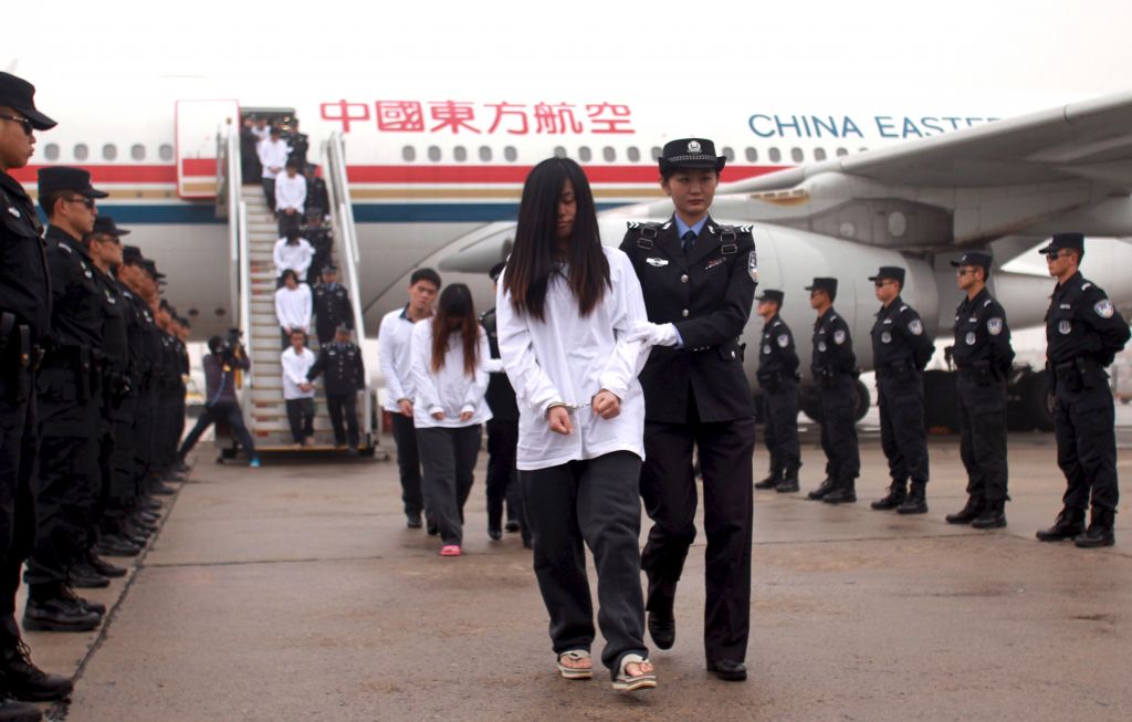 Подозреваемые в мошенничестве репатриированы в Китай, полицейские сопровождают их из самолёта в служебные автомобили