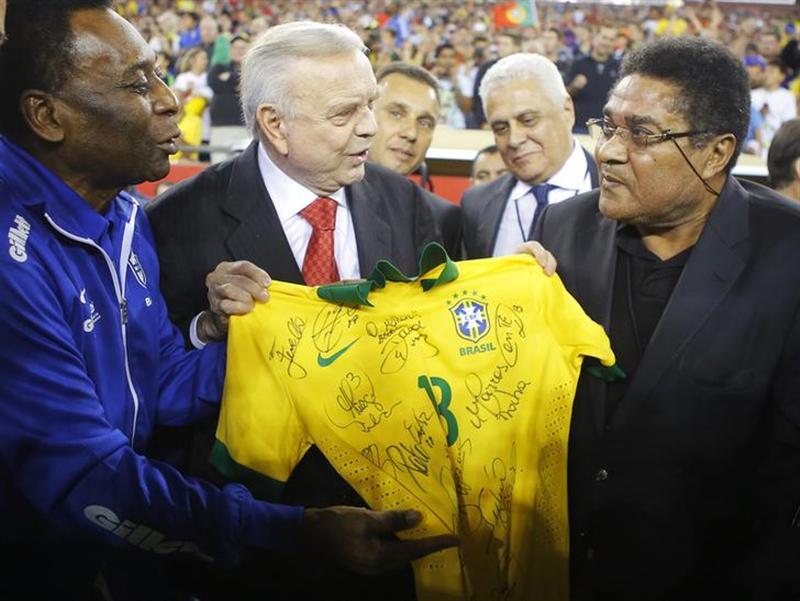 Soccer greats Pele (L) of Brazil and Eusebio (R) of Portugal hold a signed Brazil jersey in front of president of Brazil's soccer federation Jose Maria Marin before an international friendly soccer match between Brazil and Portugal in Foxborough, Massachusetts September 10, 2013